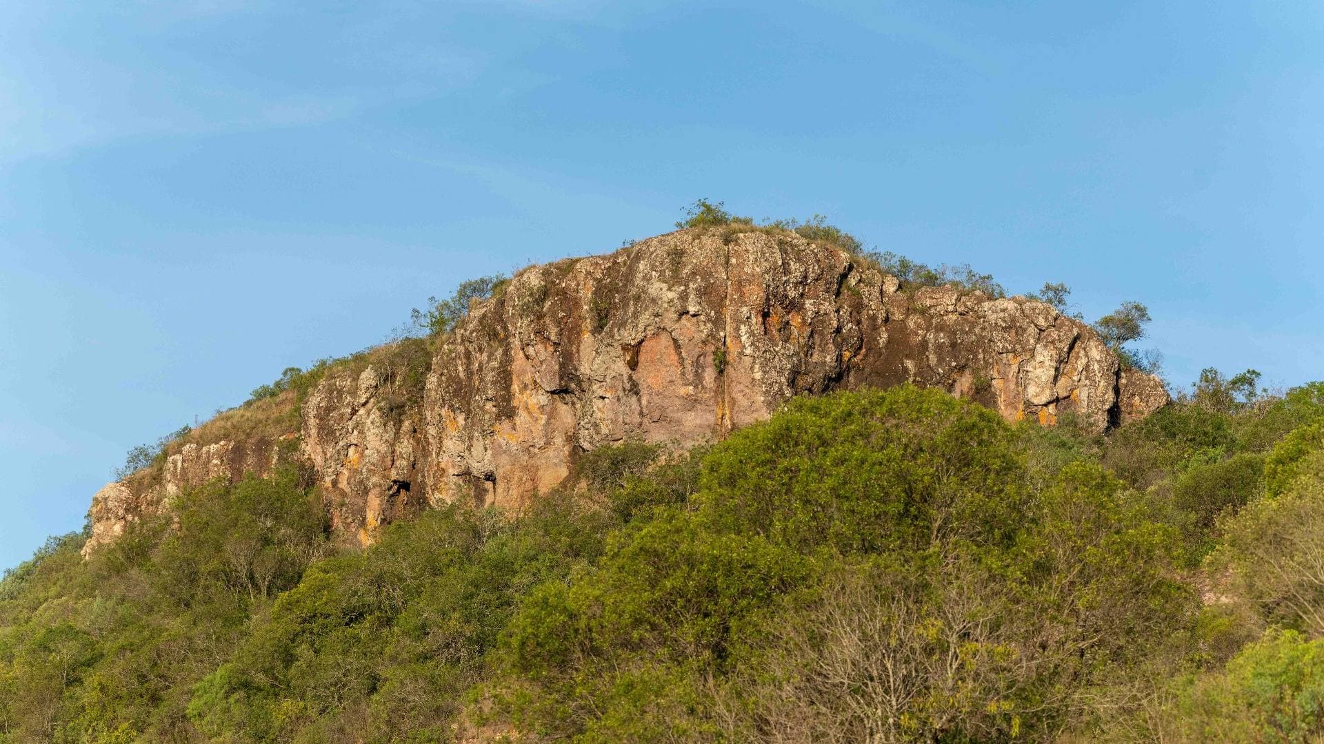 Imponente formación rocosa coronando el cerro, rodeada de denso bosque serrano nativo.